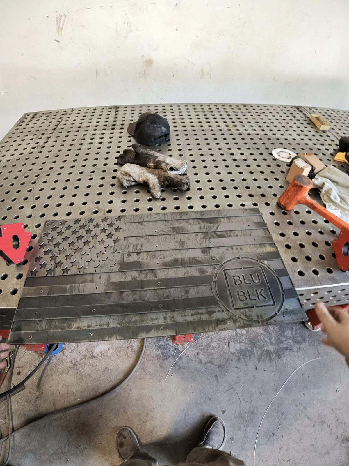 Raw laser-cut steel American flag held in the White Mountain Metals shop